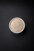 White uncooked rice in a round ceramic bowl on a dark concrete background photo