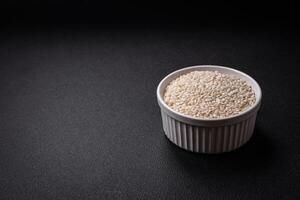 blanco sin cocer arroz en un redondo cerámico cuenco en un oscuro hormigón antecedentes foto