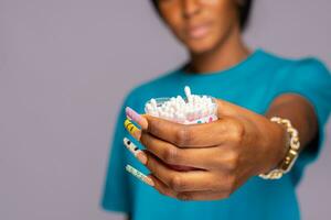 black woman holding a container of cotton buds photo