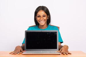 portrait of a beautiful young black woman showing her laptop screen, she is smiling photo