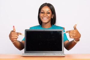 portrait of an excited beautiful young black woman pointing to her laptop screen photo