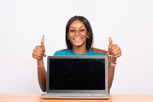 portrait of a beautiful young black woman showing her laptop screen, doing a thumbs up photo