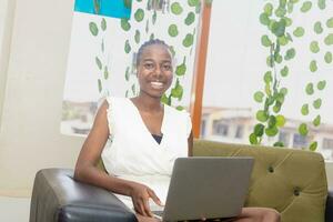 young black woman sitting on a sofa with her laptop rejoicing photo