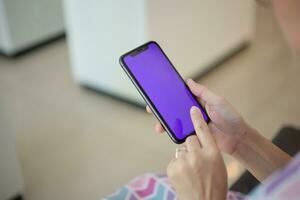 Closeup of hand using smartphone in home, hand holding phone photo