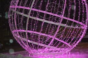 Element of evening street festive Christmas decor. Large pink electric glowing ball. photo