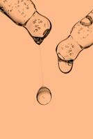 Transparent pipettes with cosmetics on a Peach Fuzz background. photo