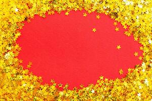 christmas shiny red background with festive golden confetti like a frame with copy space for text. photo