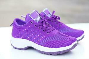 Pair of new purple sneakers. Fashionable and comfortable sport footwears. outdoor background. Concept, shoes for doing sport or exercise also can wear for traveling, hiking. photo