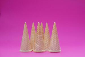 Empty crispy waffle ice cream cones isolated on pink background. Concept, part of pattern of ice creams in cone shape. Snack and dessert. copy space for text. photo