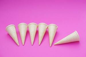 Empty crispy waffle ice cream cones isolated on pink background. Concept, part of pattern of ice creams in cone shape. Snack and dessert. copy space for text. photo