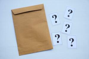 Brown envelope and paper cards of question marks. Concept. Teaching aid. Education materials for doing activity or playing investigation games about find answers. photo