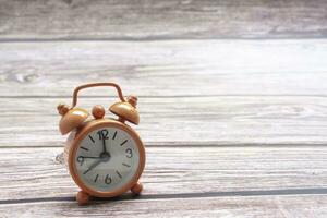 Orange alarm clock isolated on wooden desk. The clock set at 8 o'clock. photo