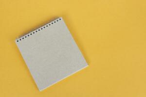 Top view of brown notepad on yellow background. Copy space. photo