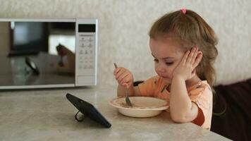 un' 3 anno vecchio bambino mangia e orologi cartoni animati utilizzando un' smartphone. cattivo abitudini. autentico scena. video