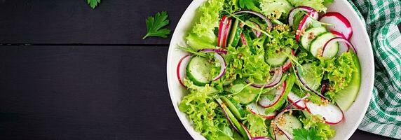 Healthy vegan food. Vegetarian vegetable salad of radish, cucumbers, lettuce  and red onion.  Top view, banner photo