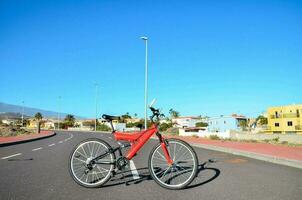 un rojo bicicleta es estacionado en el lado de el la carretera foto