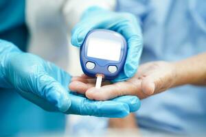 asiático médico utilizando digital glucosa metro para cheque muestra sangre azúcar nivel a tratamiento diabetes. foto