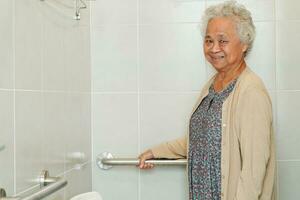 Asian elderly old woman patient use toilet support rail in bathroom, handrail safety grab bar, security in nursing hospital. photo