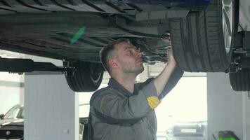 Sliding shot of auto mechanic checking SUV suspension of a lifted car video