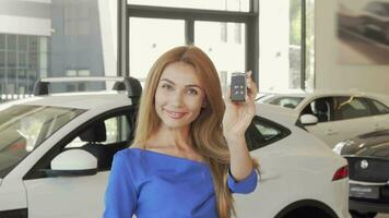 Happy female driver showing car key to the camera after buying new auto video