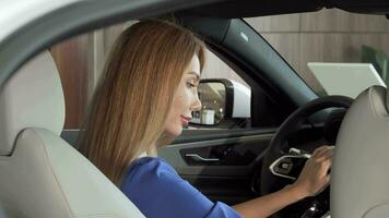 Gorgeous happy woman sitting in expensive new car smiling to the camera video