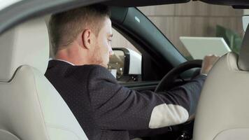 Rear view shot of a businessman sitting in a new car at the dealership video