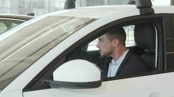 Happy handsome man examining interior of a new car sitting inside video