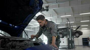 Car service technician checking oil in automobile with open hood video