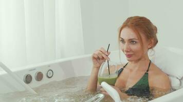 glissement coup de une magnifique femme sirotant délicieux smoothie dans tourbillon bassin une baignoire video