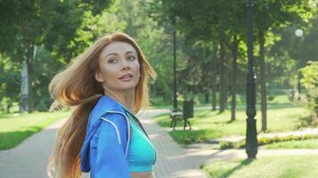 Beautiful happy sportswoman smiling to the camera while running in the park video