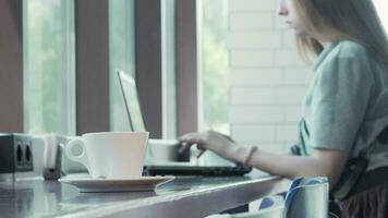 kopp av kaffe på de tabell kvinna arbetssätt på bärbar dator på de bakgrund video