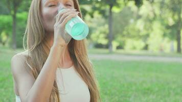 gesund passen Frau Trinken Wasser während tun Yoga im das Park video