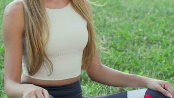 Sliding shot of a beautiful happy woman sitting on the grass in lotus position video