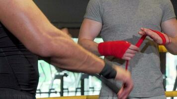 Cropped shot of two male boxers wrapping fists in bandages before fighting video