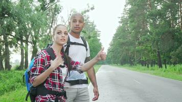 Beautiful multiracial couple hitchhiking on countryside road video