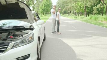 Couple calling tow truck service standing on the road with broken car video