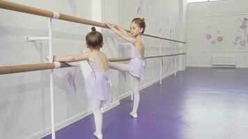 Two cute little ballerinas stretching at ballet school together video