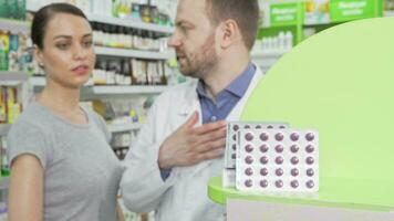 Male pharmacist offering his female customer pills in blister video