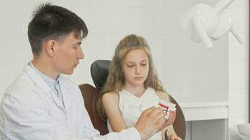 Beautiful young girl learning brushing teeth with a dentist using dental model video