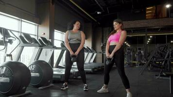 deux charmant plus Taille femelle les athlètes squat avec kettlebells à le Gym video