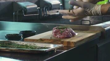 profesional cocinero agregando especias en Cerdo carne antes de Cocinando video