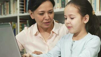 feliz mãe e filha usando computador portátil enquanto estudando video