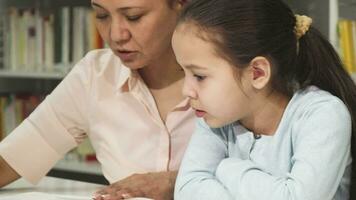 cerca arriba de un linda pequeño niña leyendo un libro con su madre video