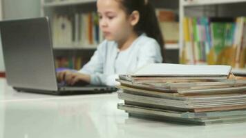 weinig meisje gebruik makend van laptop Bij school- aan het studeren aan het doen huiswerk video