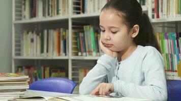 mignonne peu fille rêver tandis que en train de lire une livre à le bibliothèque video