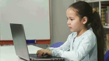 Lycklig skön asiatisk liten flicka leende medan använder sig av bärbar dator video