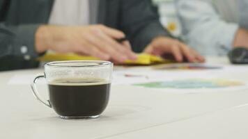 Close up of a cup of coffee on the table businesspeople working on the background video