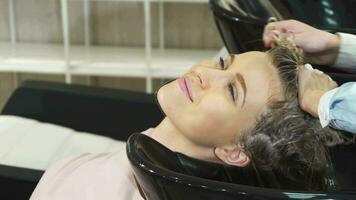 stänga upp av en skön kvinna få henne hår tvättades på de frisör salong video