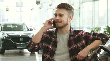 alegre bonito homem falando em a telefone às a carro concessionária video