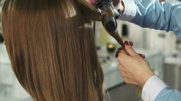 Rückansicht schließen oben von ein Frau bekommen ihr Haar zusammengerollt durch ein Fachmann Friseur video